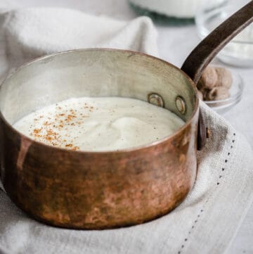 white sauce in a saucepan surrounded by ingredients