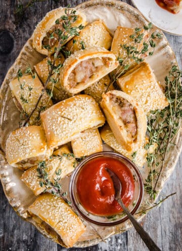 sausage rolls on a plate with a bowl of ketchup