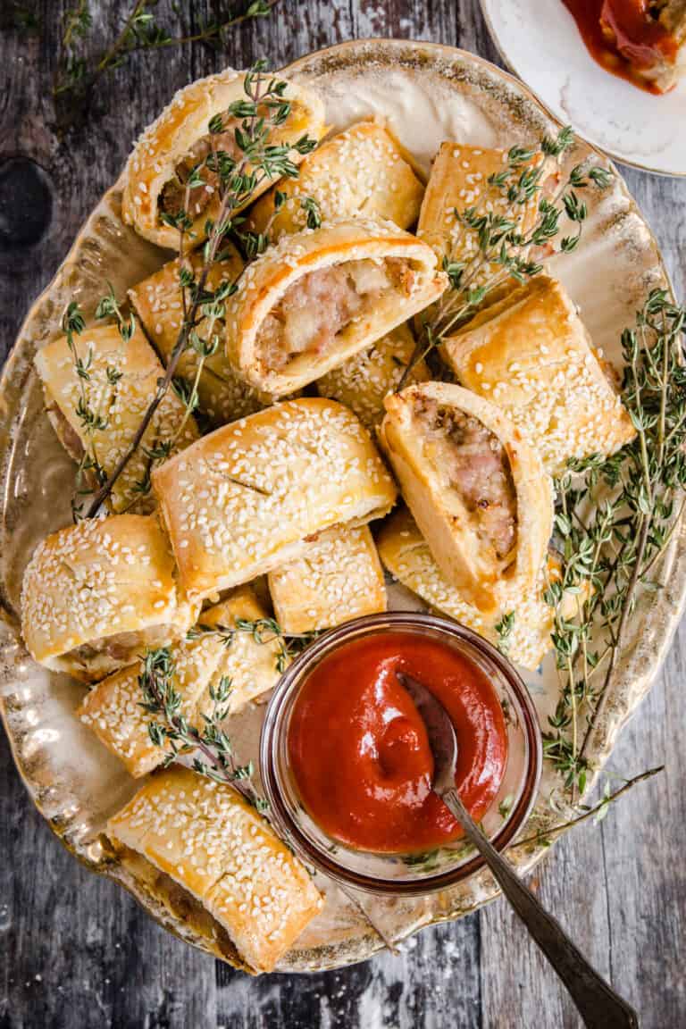 sausage rolls on a plate with a bowl of ketchup