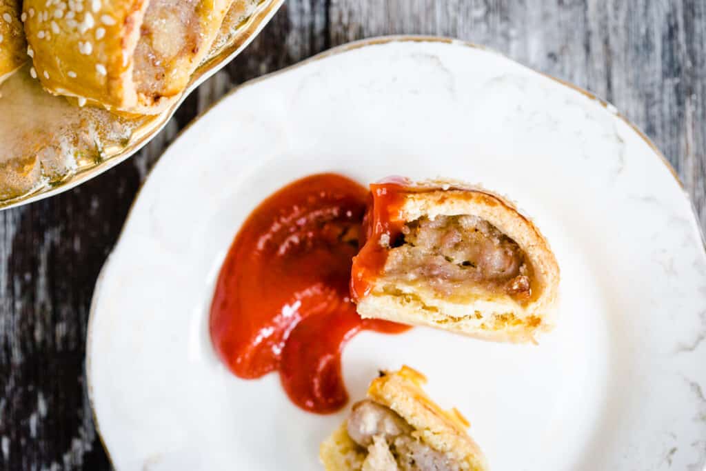 Sausage roll dipped in ketchup on a plate