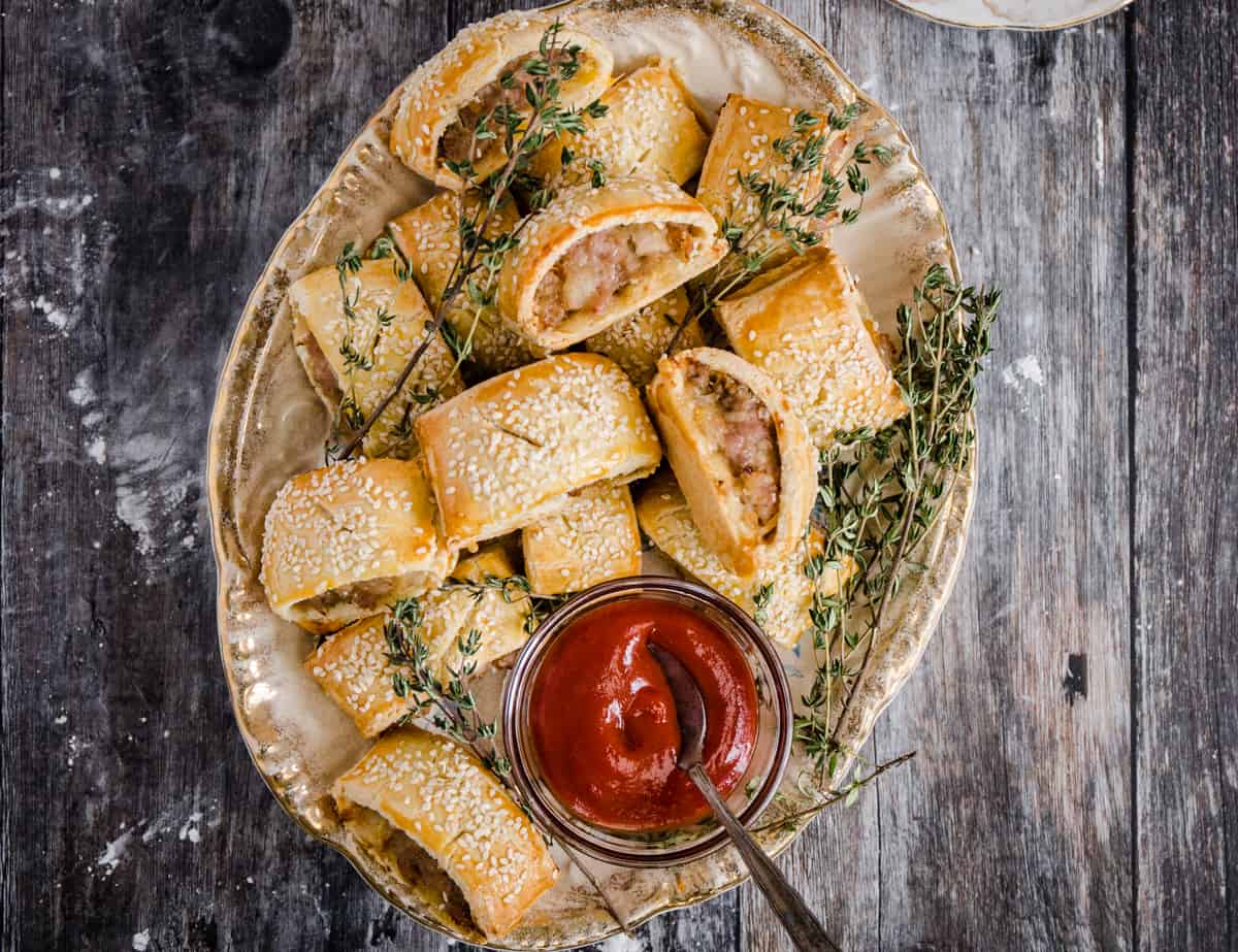 sausage rolls on a plate with a bowl of ketchup