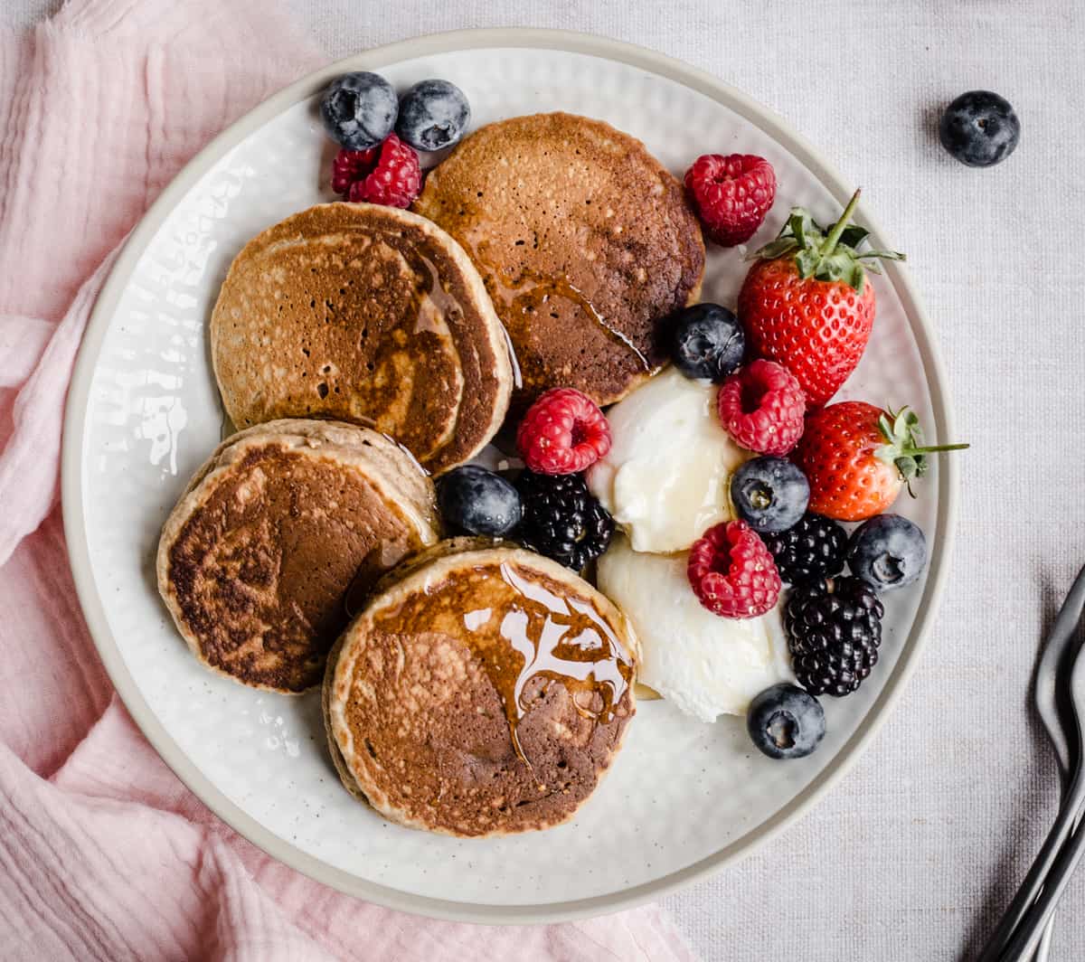 Pancakes on a plate with berries next to forks