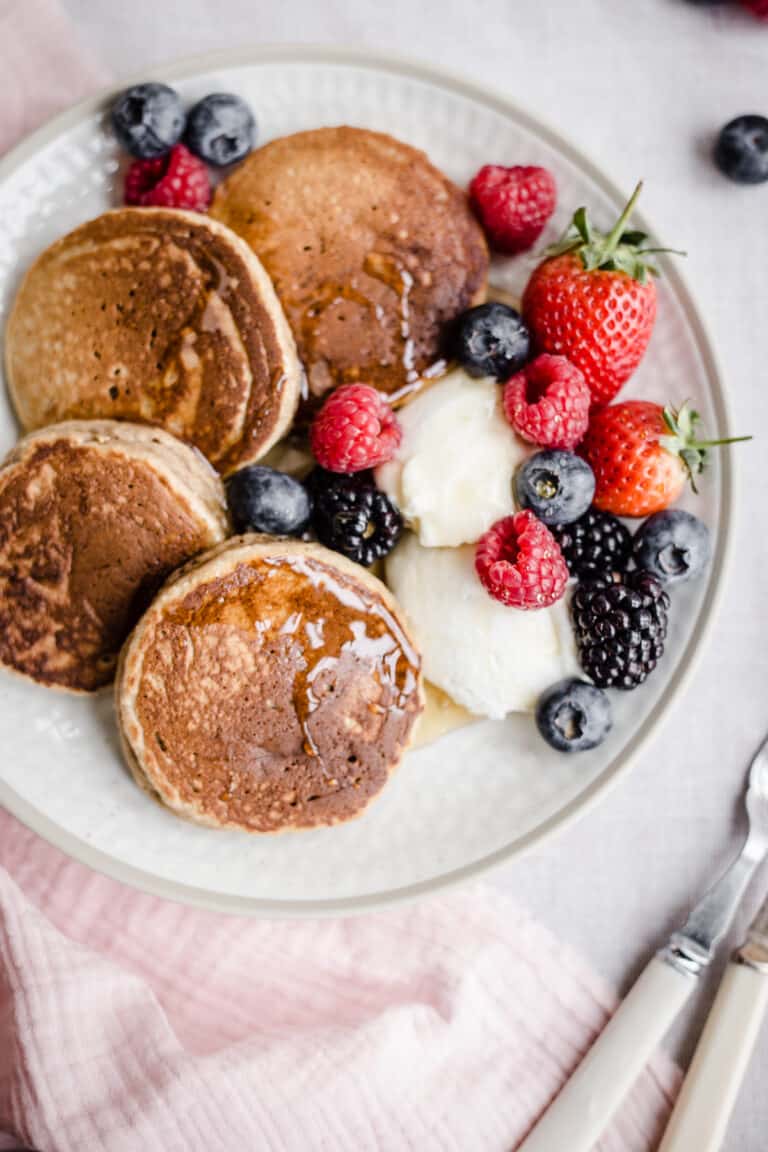 Pancakes on a plate with berries next to forks