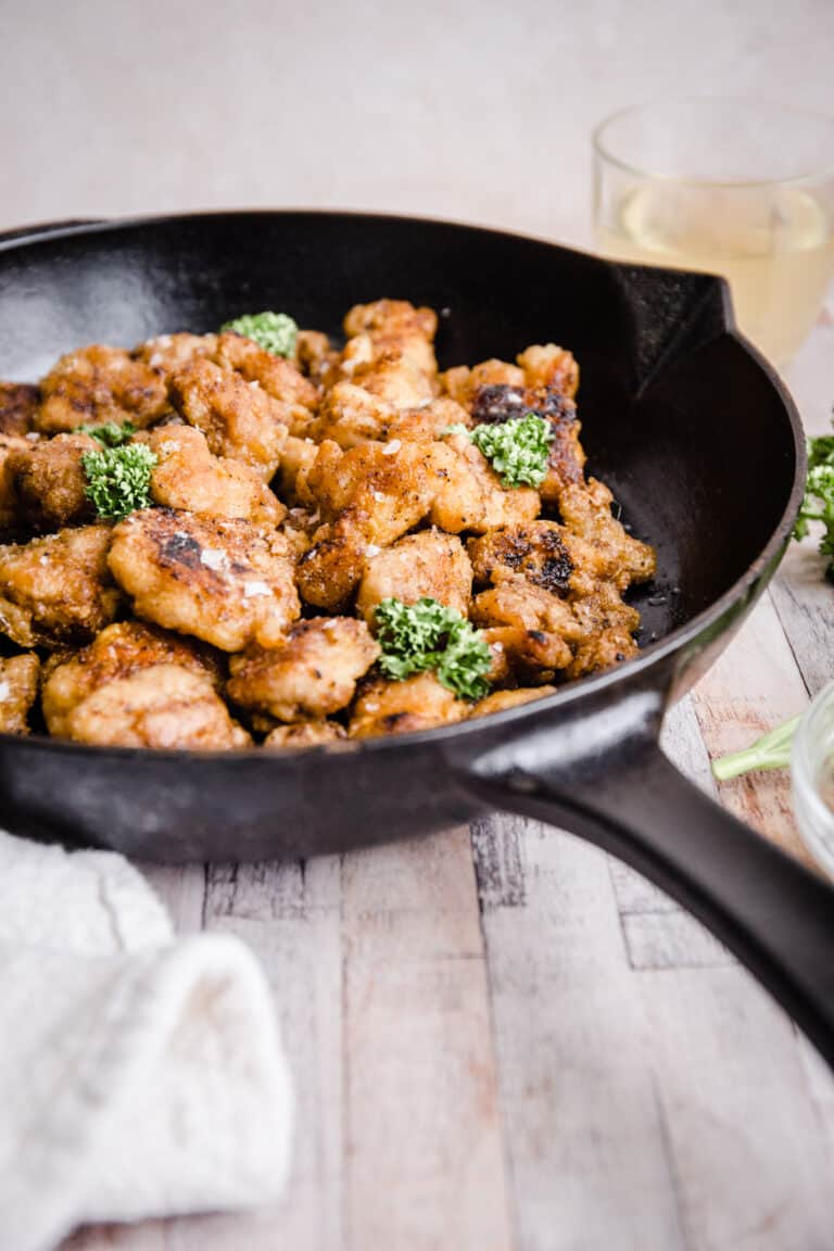 Gluten-Free Fried Popcorn Chicken in a cast iron skillet on table next to sauce and parsley