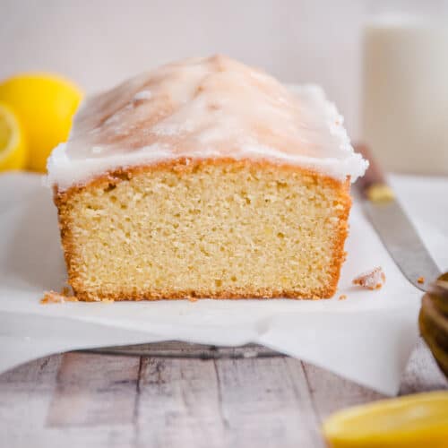 lemon drizzle cake on rack next to knife and lemons