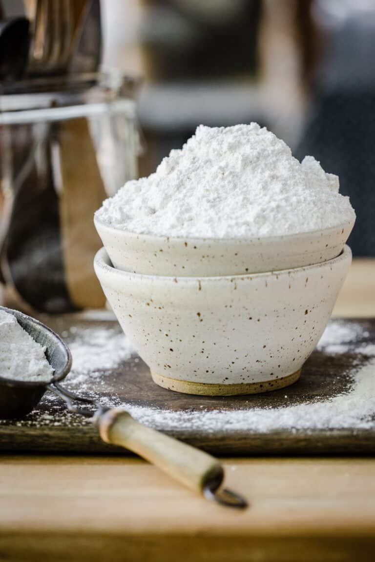 flour in a bowl on a wooden board next to scoop