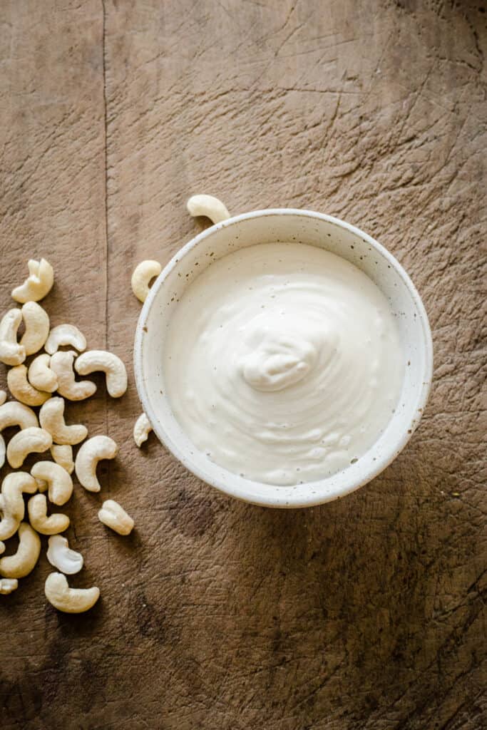 bowl of cashew cream on board with nuts