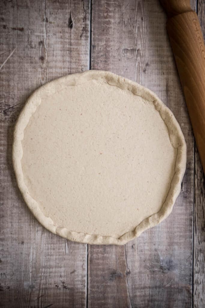 rolled out pizza dough next to rolling pin