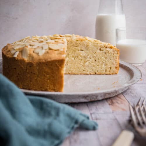 pear and almond cake on plate on table with cloth, cutlery and milk