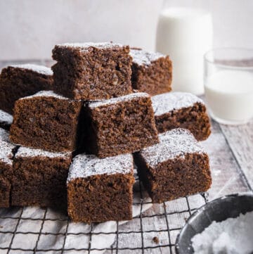 Sticky Gingerbread Cake stacked on a wire rack next to milk