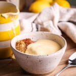 Lemon custard poured over lemon sponge pudding in a bowl.