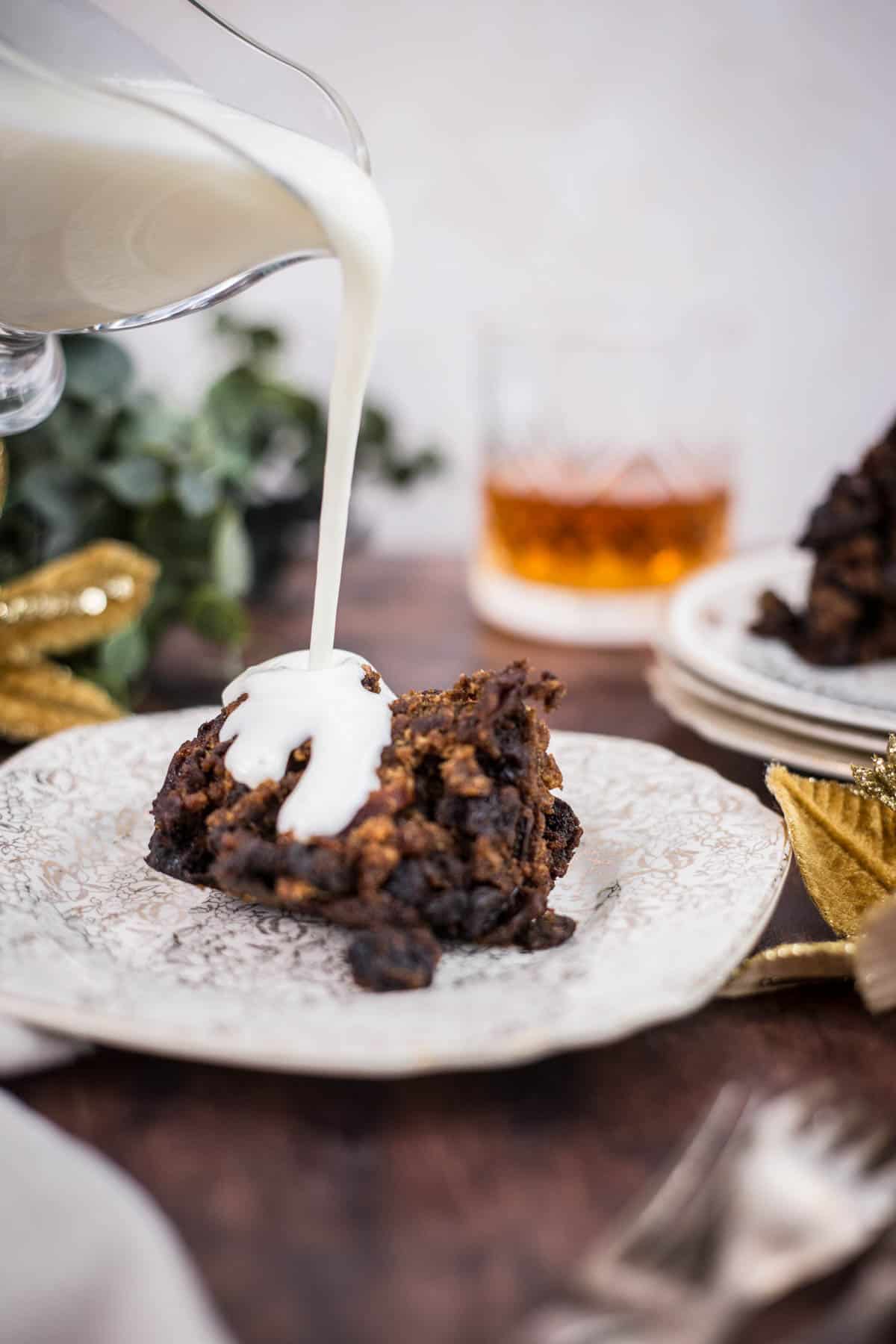 Brandy sauce poured over a plate of christmas pudding on festive table