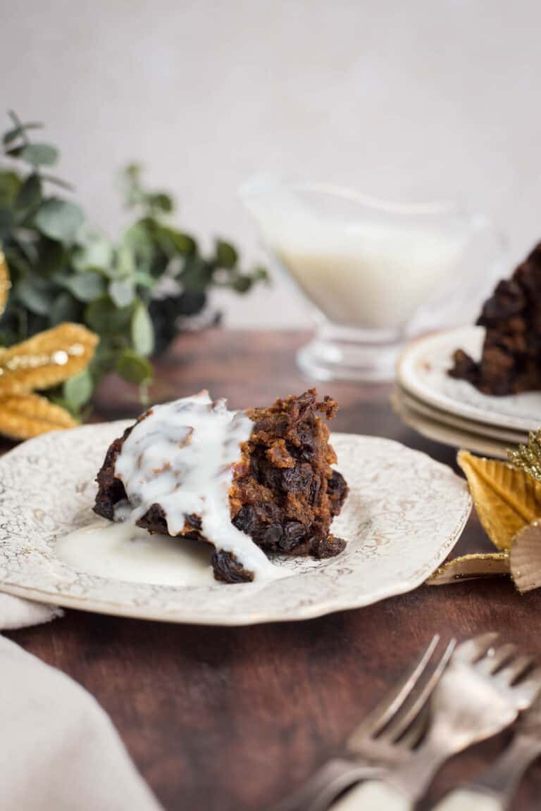 Brandy sauce poured over a plate of christmas pudding on festive table