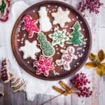 Wooden plate full of Christmas Cookies with Christmas Decorations surrounding