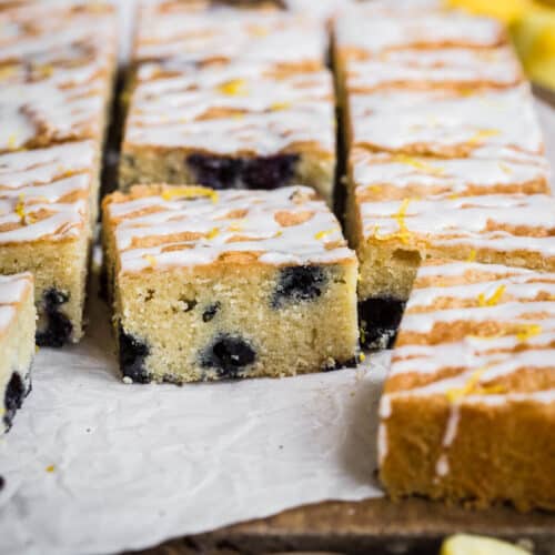 Slices of Gluten Free Lemon Drizzle Traybake with Blueberries on a wooden board