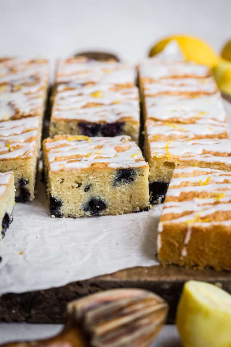 Slices of Gluten Free Lemon Drizzle Traybake with Blueberries on a wooden board