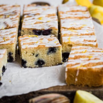 Slices of Gluten Free Lemon Drizzle Traybake with Blueberries on a wooden board