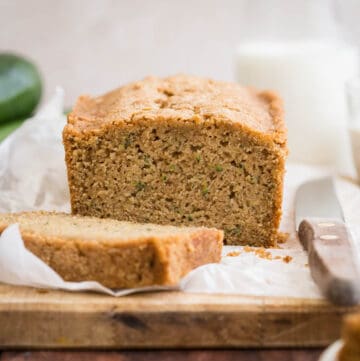 Gluten Free Zucchini Bread on wooden board , sliced. Next to courgette and milk.