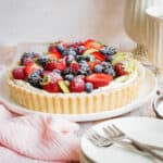 Gluten-Free Fruit Tart on a plate next to pink napkin, plates, forks and teapot and cup