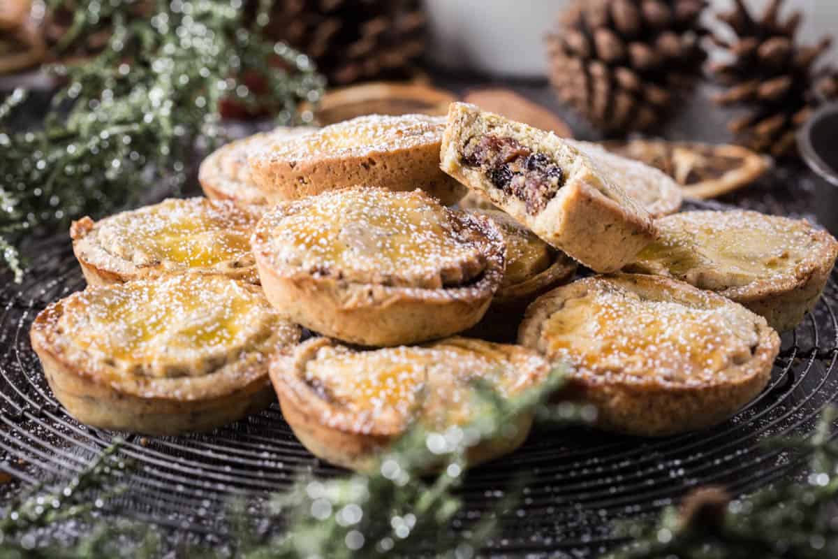 mince pies piled high with bite taken out of the top one showing juicy mincemeat filling.