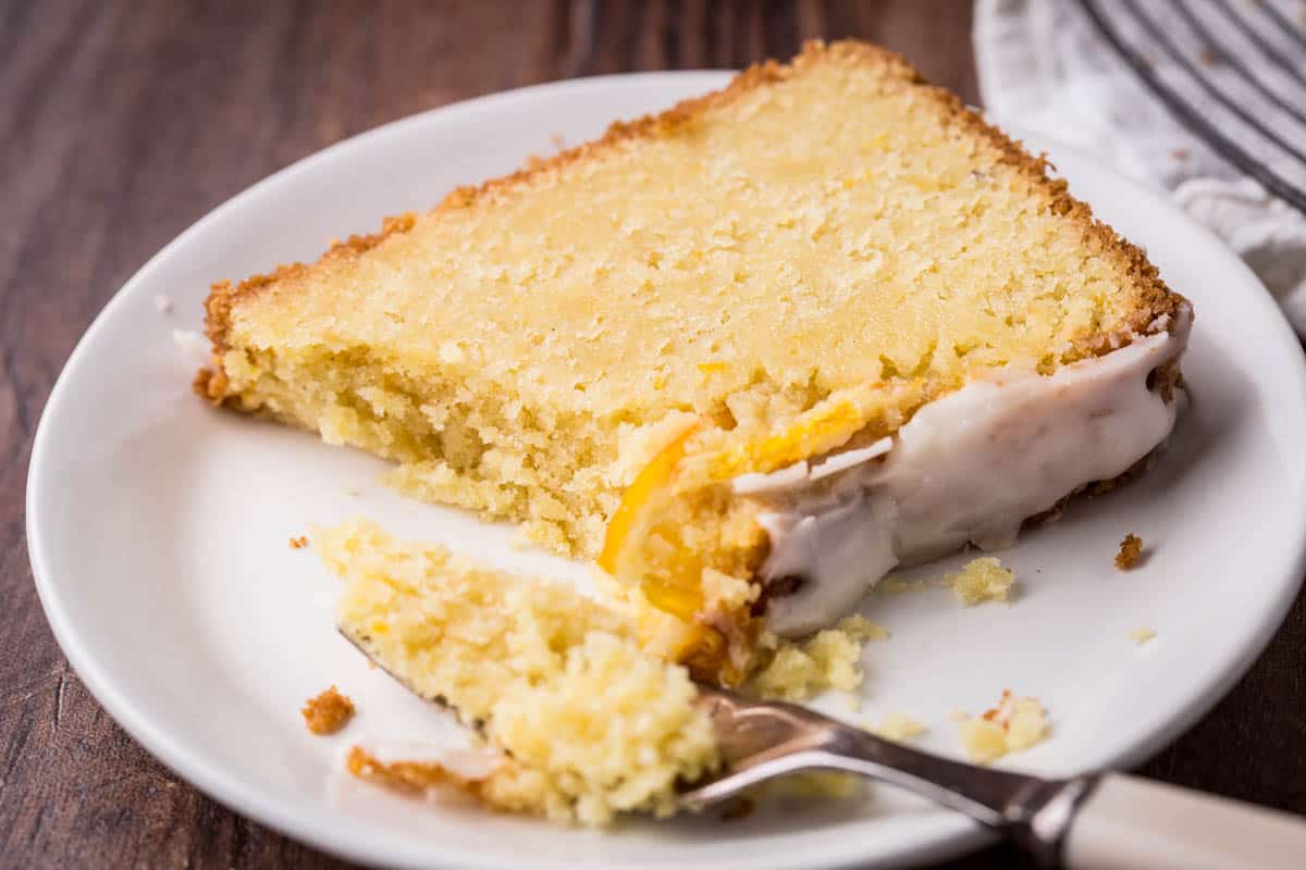 slice of orange cake on a plate with fork ful taken out, the crumb is not crumbly.