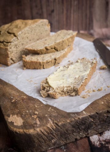 Slice of soda bread slathered with butter and a bite taken out.