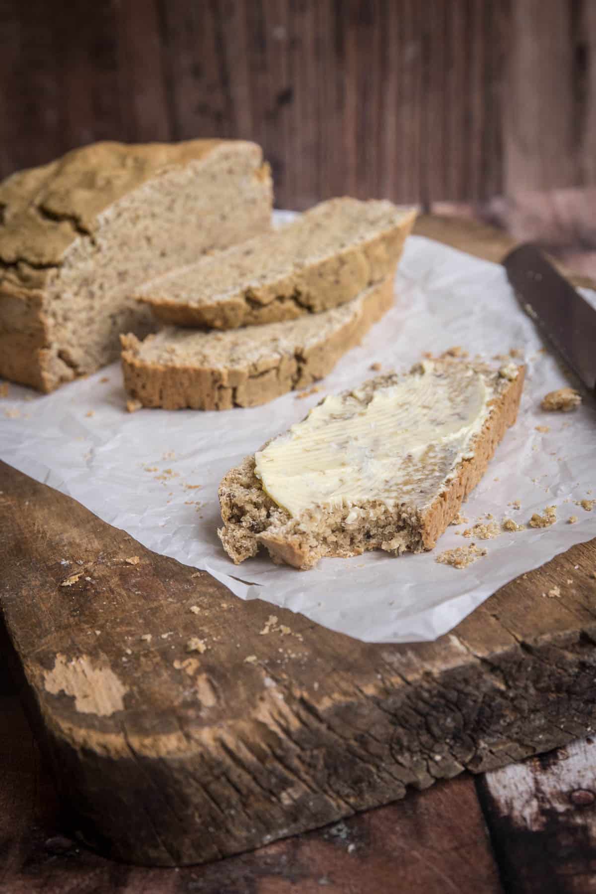 Slice of soda bread slathered with butter and a bite taken out.