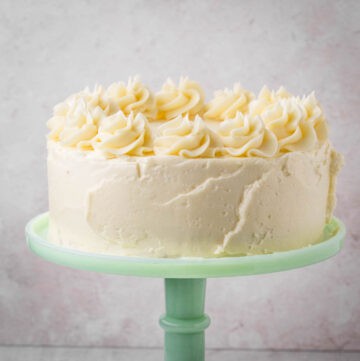 Layer Cake covered in swiss meringue buttercream with piped decoration on green cake stand.