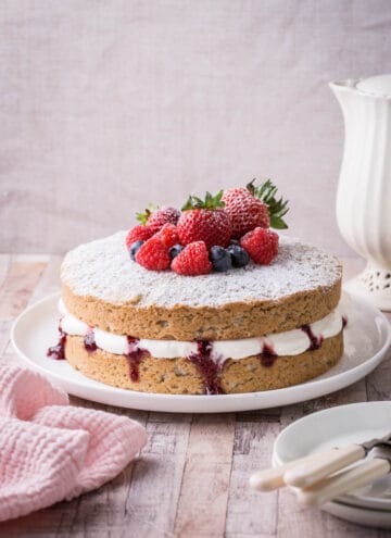 Gluten-Free Vegan Vanilla Cake on Cake plate with fresh fruit piled on top.