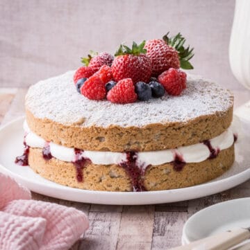 Gluten-Free Vegan Vanilla Cake on Cake plate with fresh fruit piled on top.