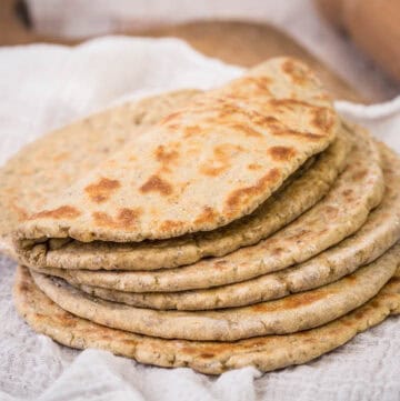 A pile of Gluten-Free Flatbreads. The top one is softly folded in half.