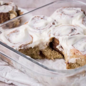 Pan of gluten-free cinnamon rolls with 2 rolls removed showing soft and fluffy inside.