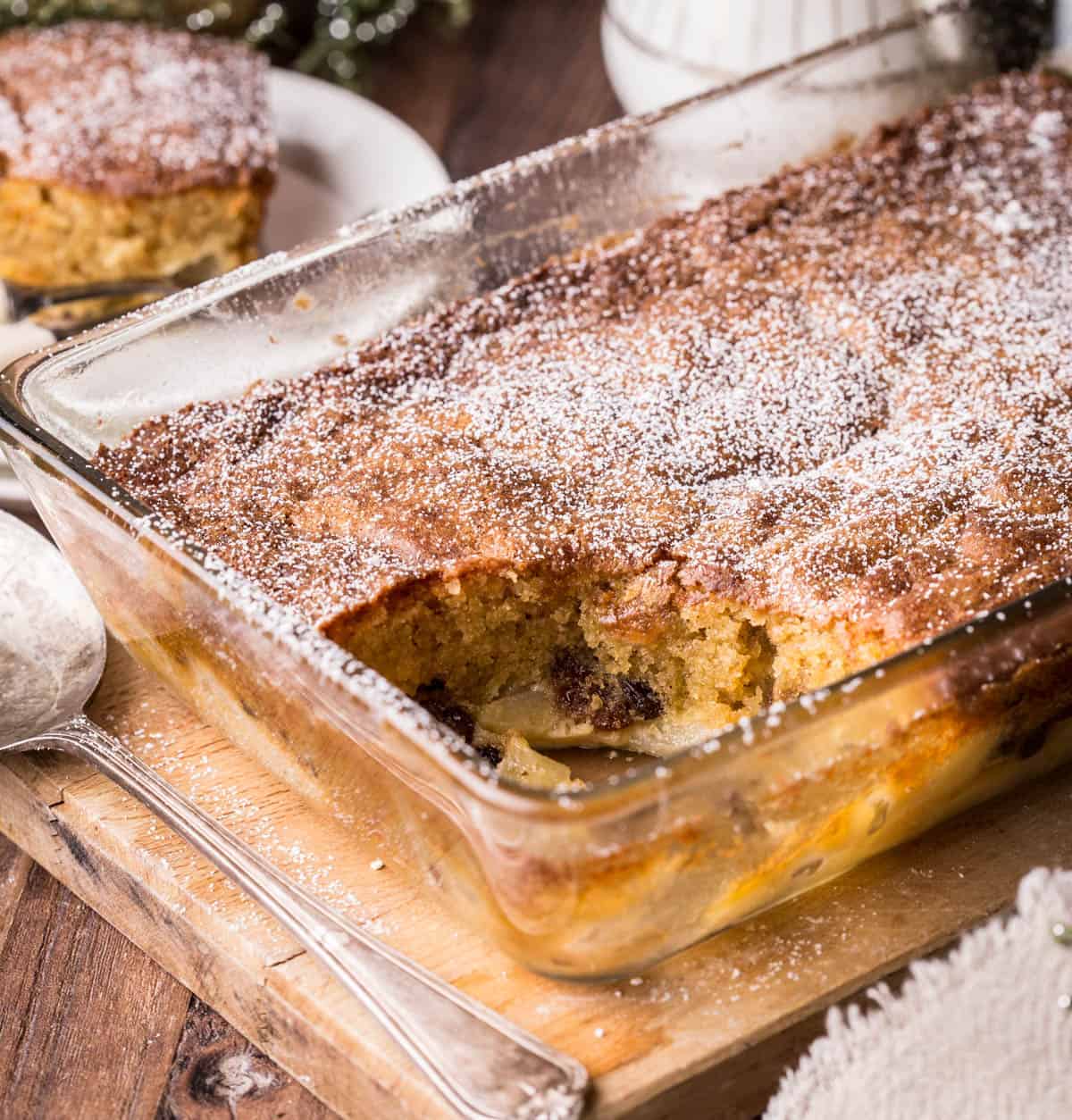Large baking dish of Bramley Apple Mincemeat Pudding with portion spooned out showing light and fluffy sponge.