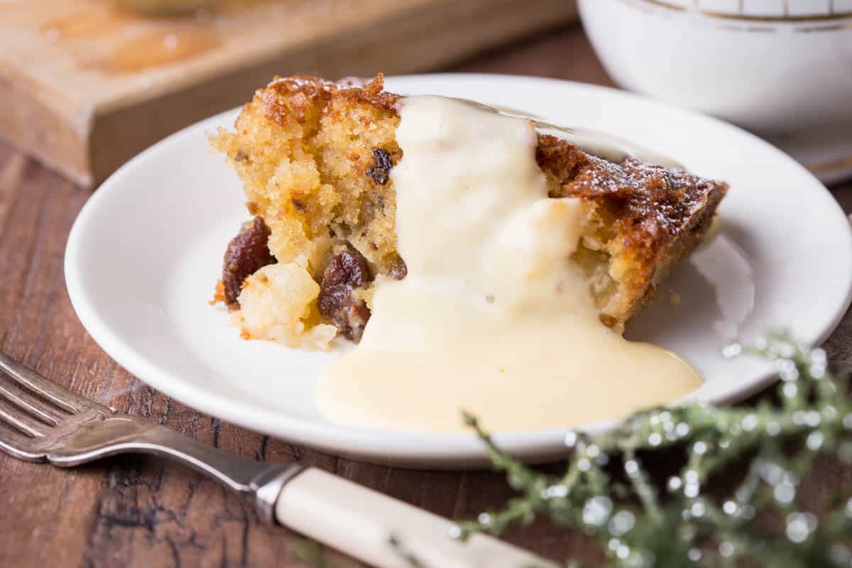 Plate of Bramley Apple Mincemeat Pudding drizzled in custard showing light and fluffy sponge.
