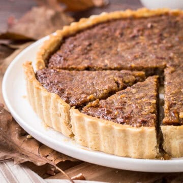 Gluten-Free Treacle Tart with Pecans on a plate with 2 slices cut.