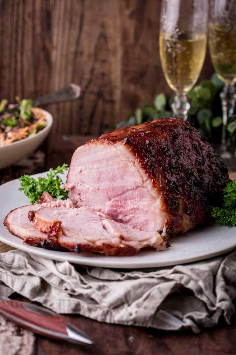 A whole Christmas Ham sliced on a plate showing tender succulent meat inside with crisp glazed surface.