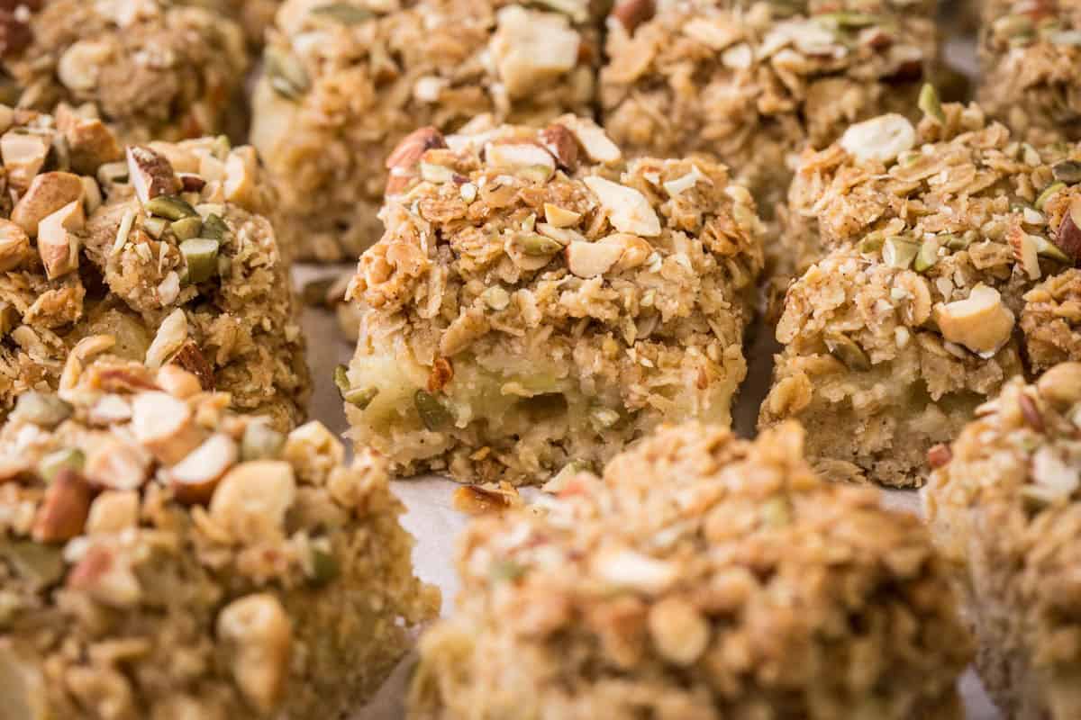 Apple flapjacks shown from the side so you can see the nutty topping, the buttery oat mixture and the fluffy bramley apple middle.