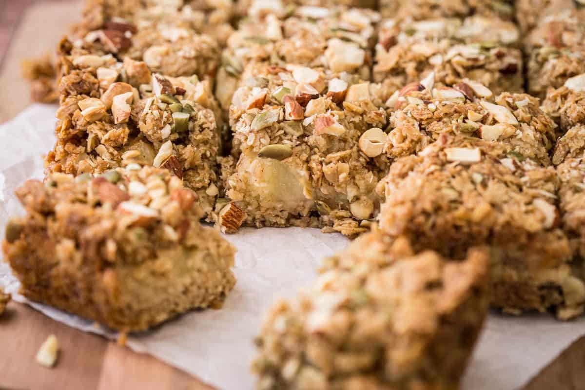 Apple flapjacks shown from the side so you can see the nutty topping, the buttery oat mixture and the fluffy bramley apple middle.