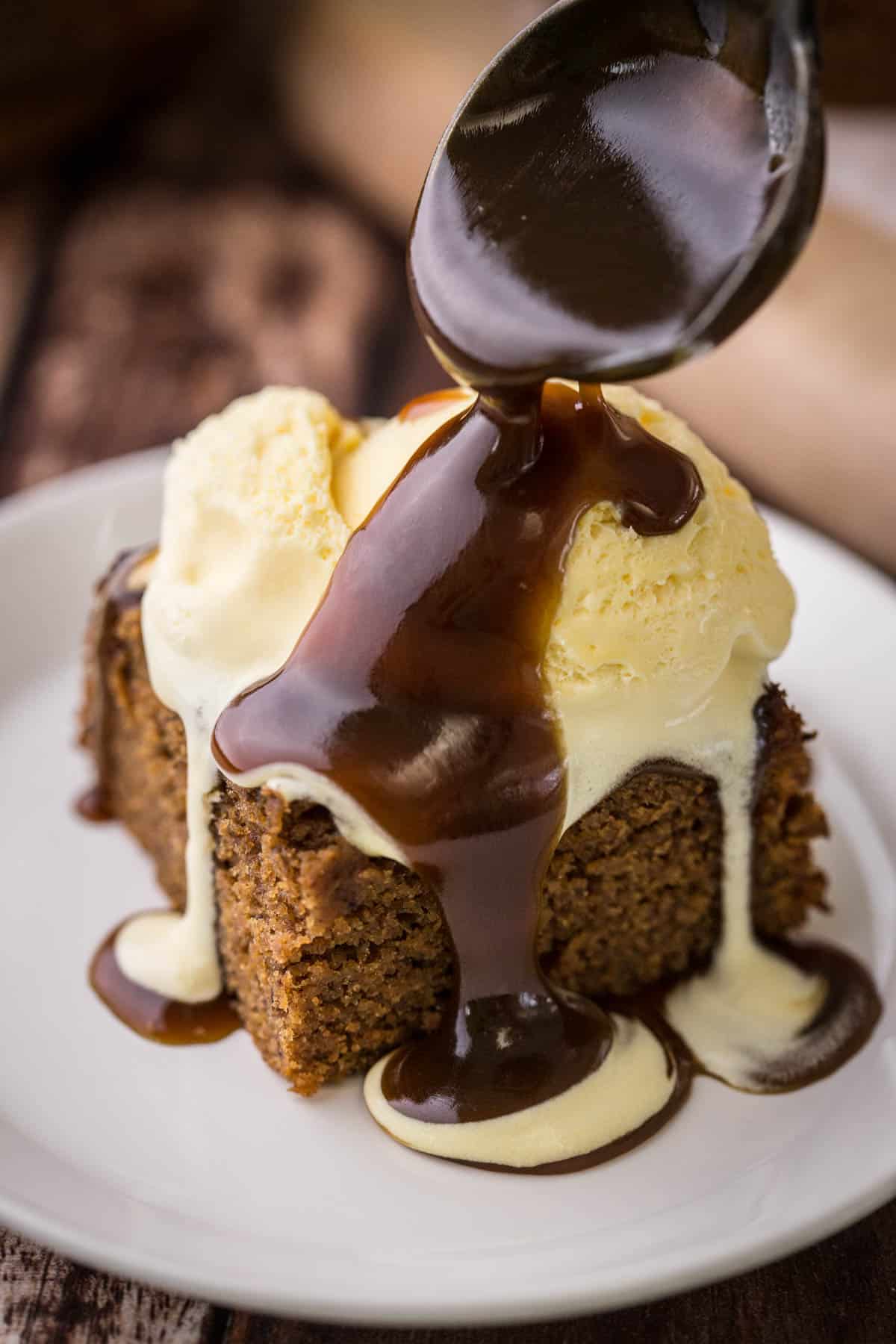 Sticky Toffee Sauce poured over Sticky Toffee Pudding with ice cream.