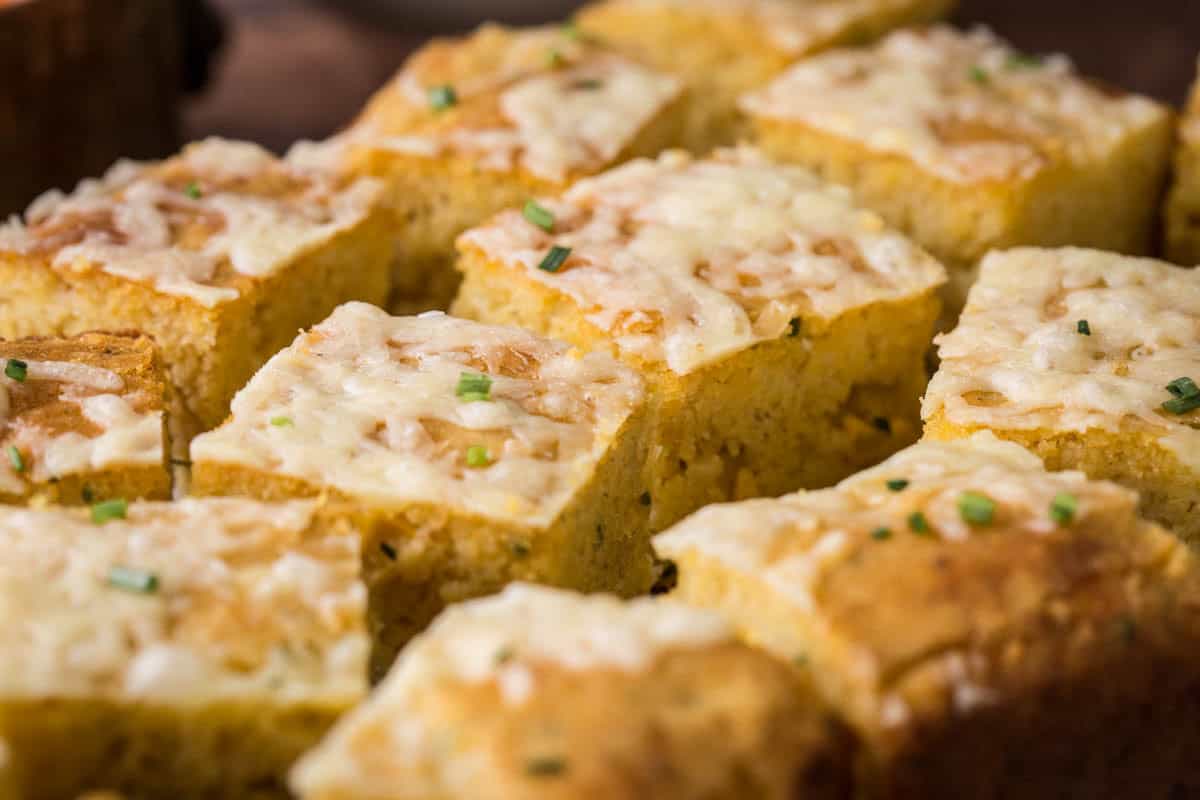 Sliced gluten-free cheddar chive cornbread on a serving board.