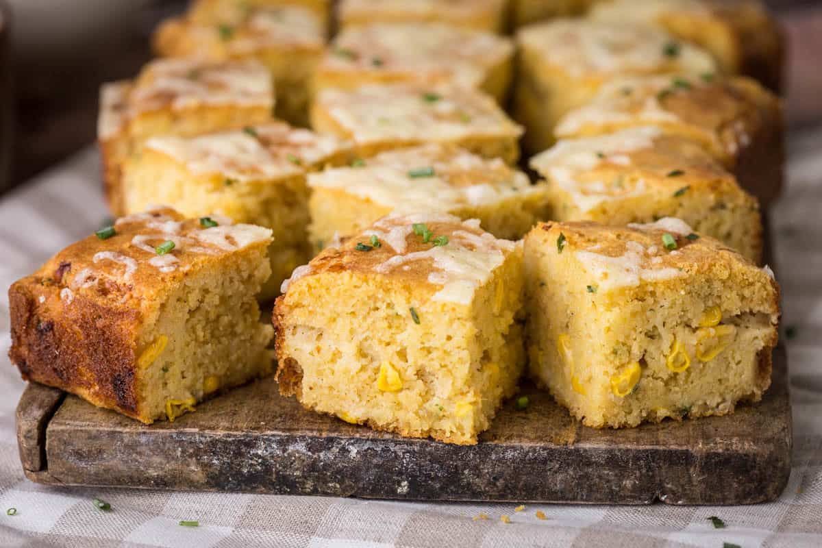 Sliced gluten-free cheddar chive cornbread on a serving board.
