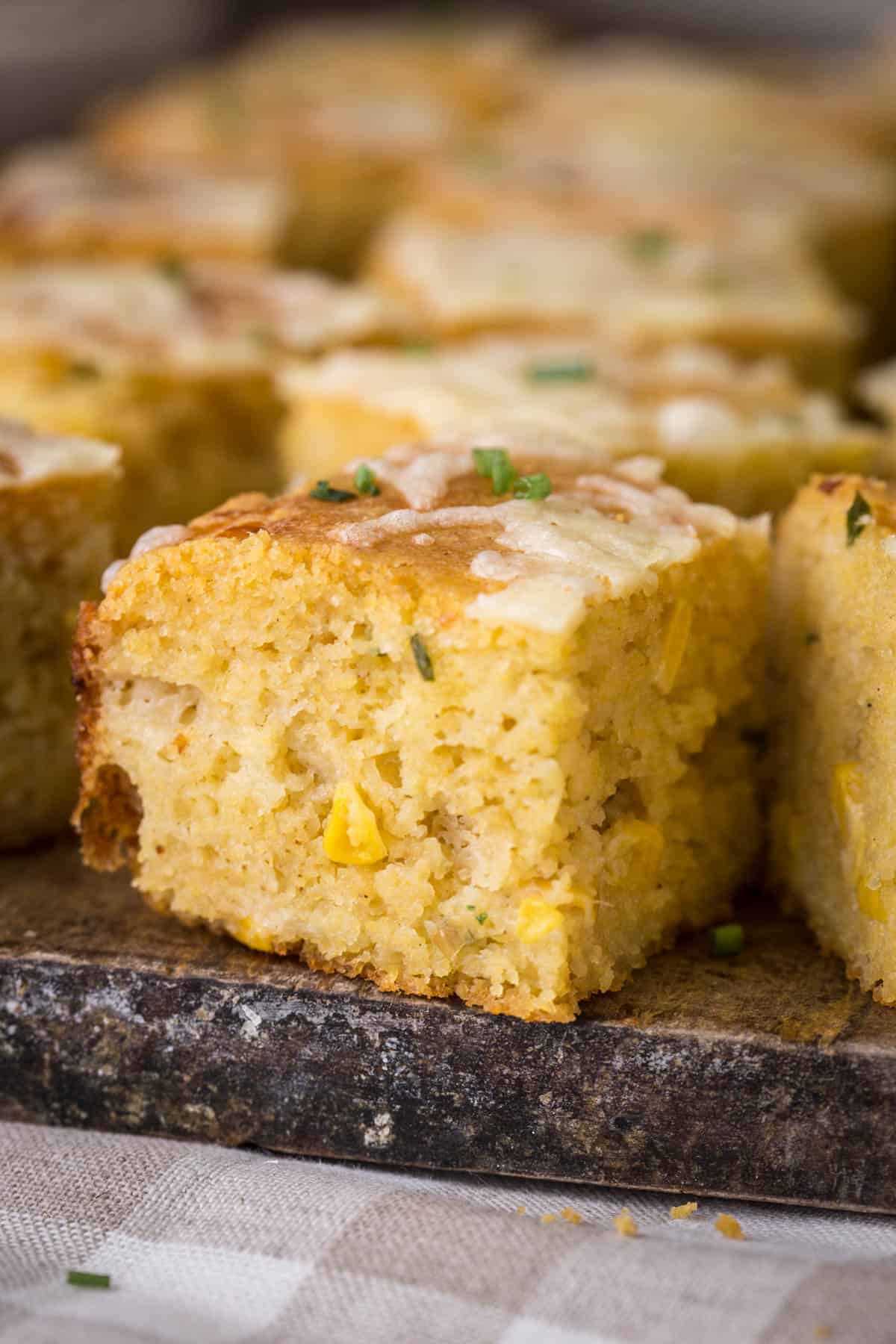 Sliced gluten-free cheddar chive cornbread on a serving board.