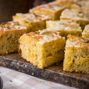 Sliced gluten-free cheddar chive cornbread on a serving board.
