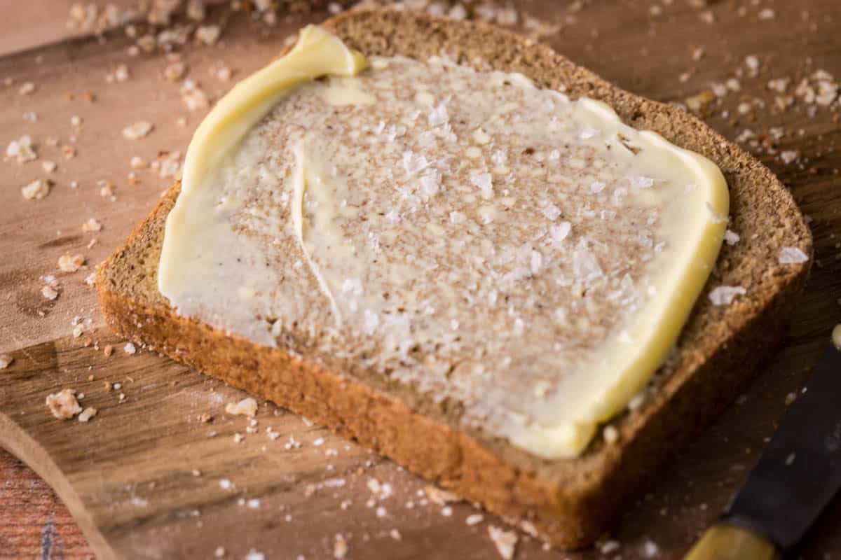 Slice of Gluten-Free Brown bread spead with butter and salt.