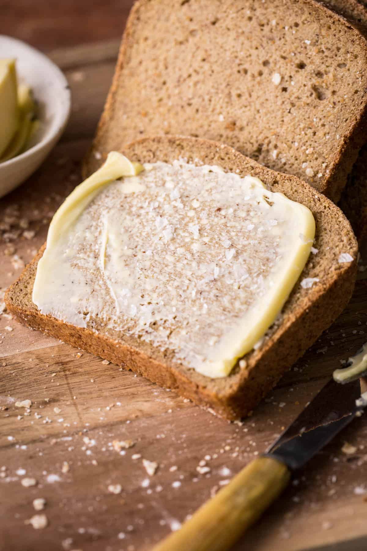 Slice of Gluten-Free Brown bread spread with butter and salt.