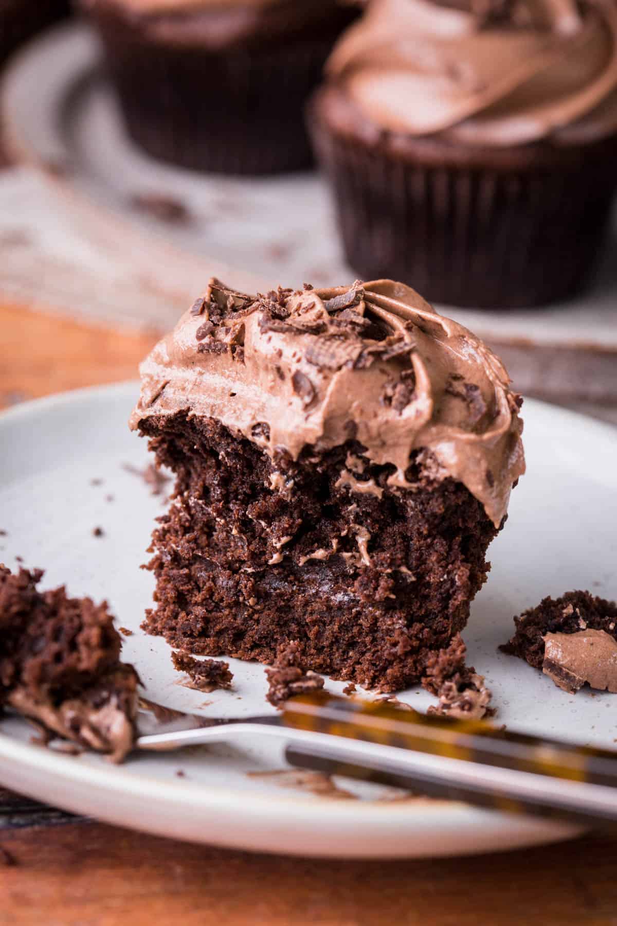 Vegan Chocolate Cupcake with forkful taken out showing the soft and fluffy inside and creamy chocolate buttercream.