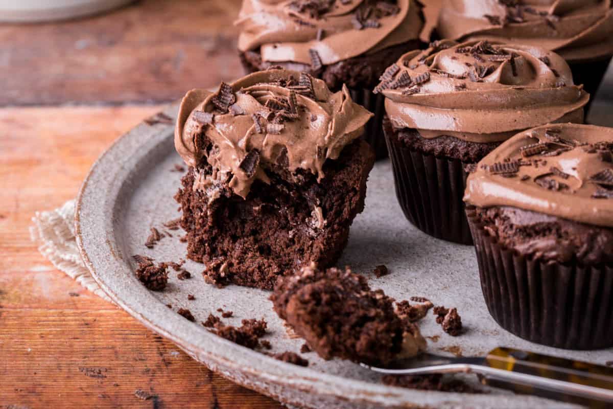 Vegan Chocolate Cupcake with forkful taken out showing the soft and fluffy inside and creamy chocolate buttercream.