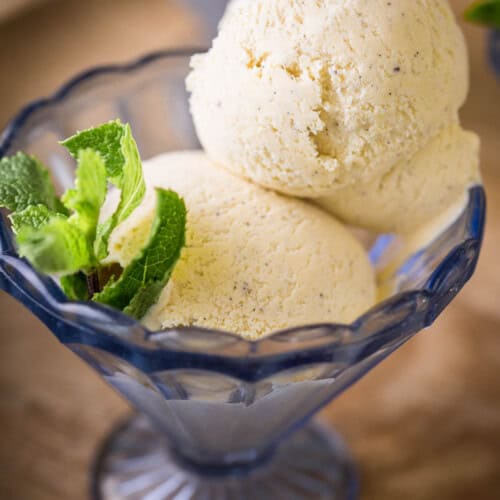 Homemade Vanilla Ice Cream in a glass dish decorated with a sprig of mint.