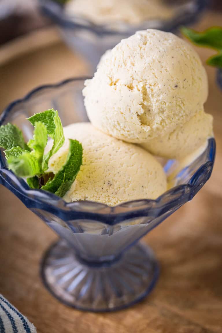 Homemade Vanilla Ice Cream in a glass dish decorated with a sprig of mint.