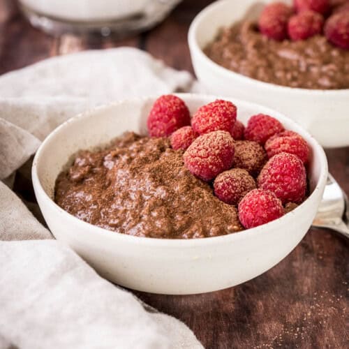 Chocolate Porridge in a bowl with fresh raspberries and dusting of cocoa powder.